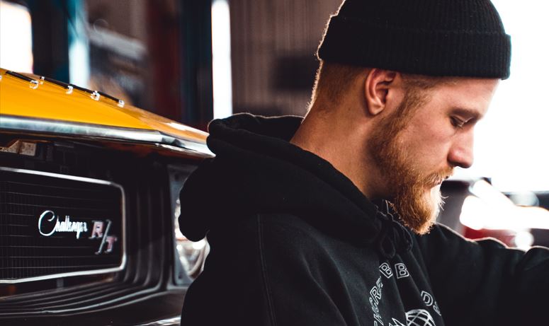 man with beard inspecting a classic vehicle