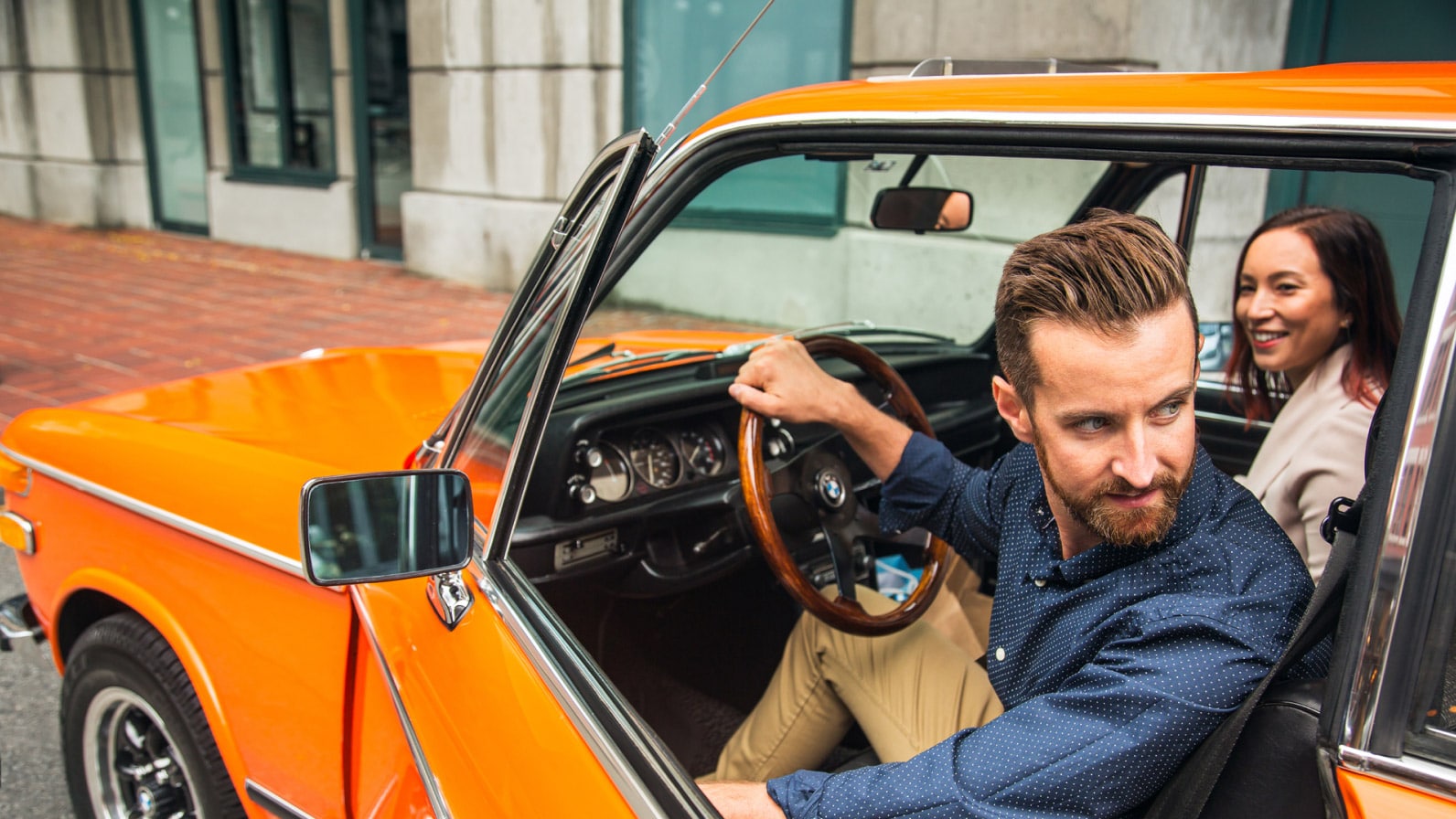 happy couple in an orange classic car