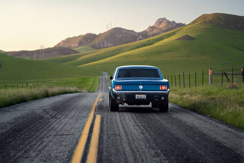 Classic Ford mustang cruising through rolling hills 
